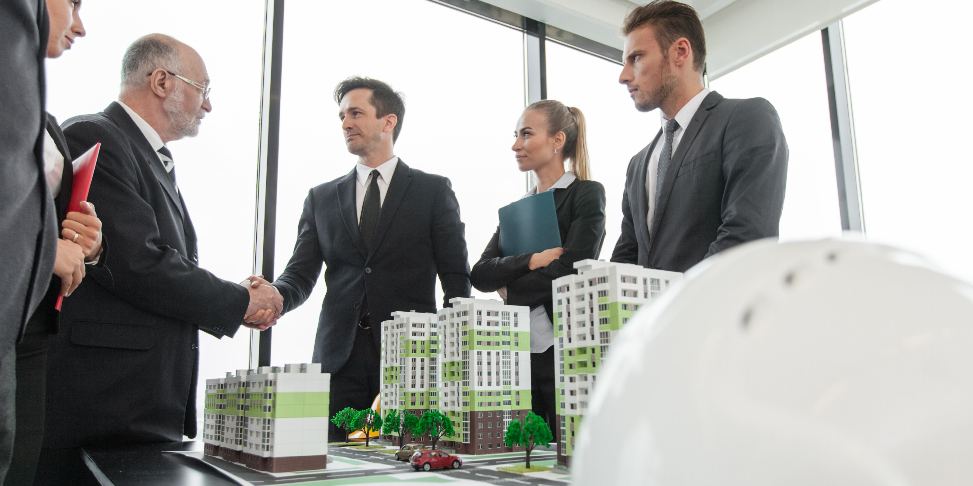Business professionals shaking hands during a meeting about real estate development and municipal liens.